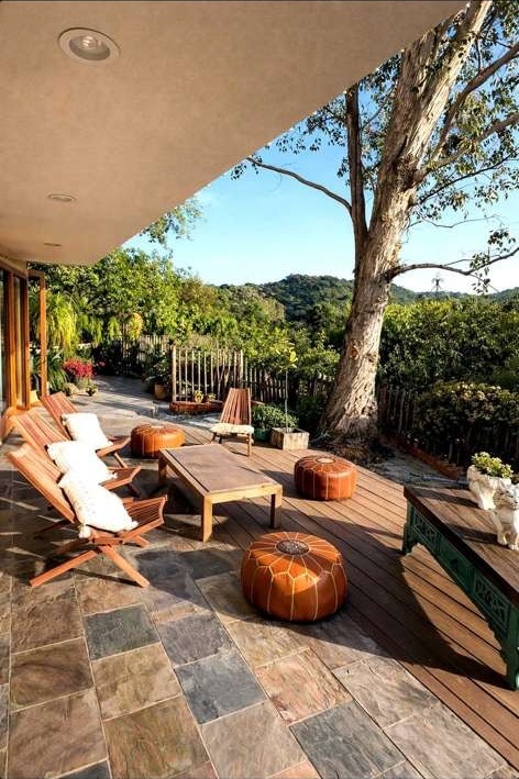 Wooden deck with lounge chairs, leather poufs and oak trees overlooking the Woodland Hills